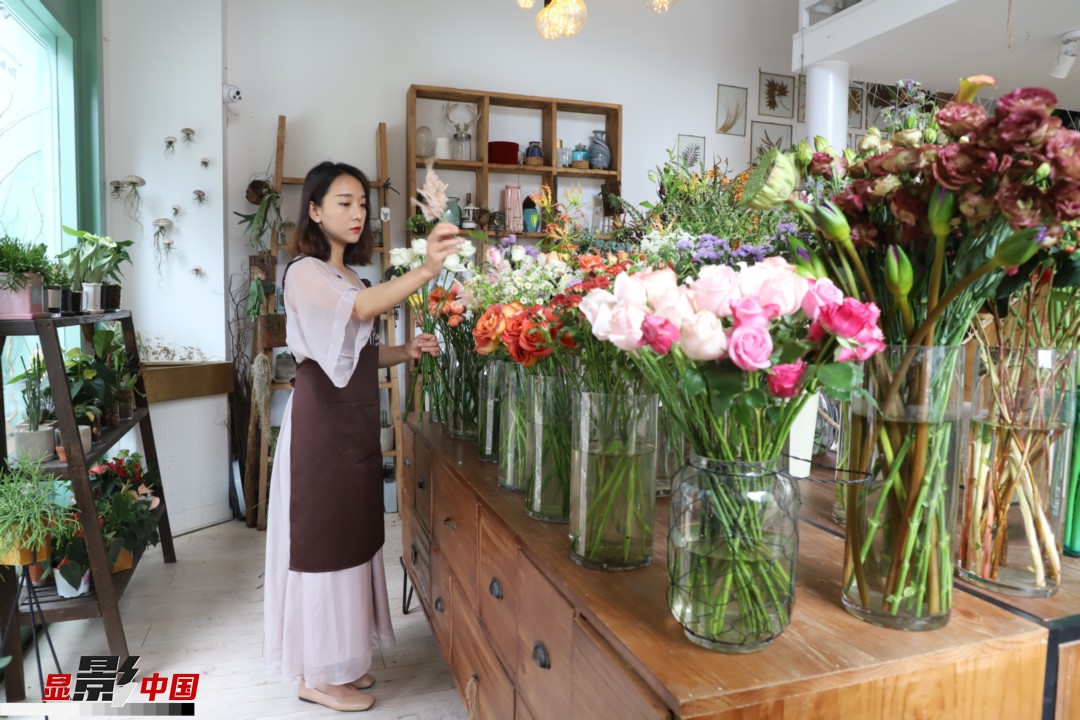 王黎媛是一名河南姑娘，在昆明念完大學(xué)后，就再也舍不下春城的藍(lán)天陽光、青山碧水，更舍不下這里的四時繁花，于是就干脆留了下來，成了一名媒體人。2017年的時候又毅然辭去工作，創(chuàng)業(yè)開起了花店，成了都市里的一名“花房姑娘”。圖為王黎媛在自己的花店中整理鮮花。新華網(wǎng) 周亞平/攝 念新洪/文